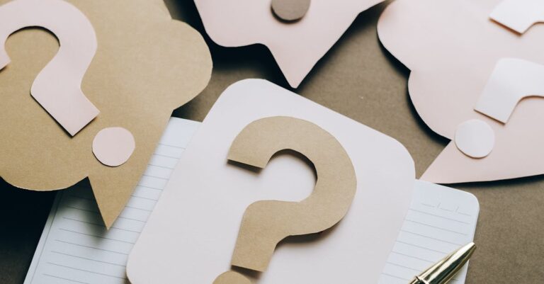 Artistic paper question marks on an open notebook with a pen, symbolizing curiosity and creativity.